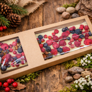Biała czekolada z malinami, borówkami i owocami leśnymi w ekologicznym opakowaniu na drewnianym tle