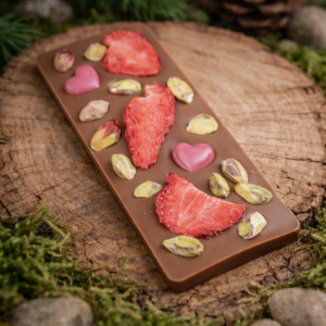 czekolada mleczna z truskawką i pistacją na drewnianym tle