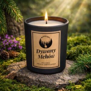 Świeca sojowa „Dywany Mchów” w czarnym, matowym szkle ustawiona na kamieniu w leśnej aranżacji z zielonym mchem i fioletowymi kwiatami.