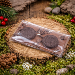 Czekolada mleczna z ciasteczkami typu Oreo ułożona na drewnianym krążku w leśnej aranżacji