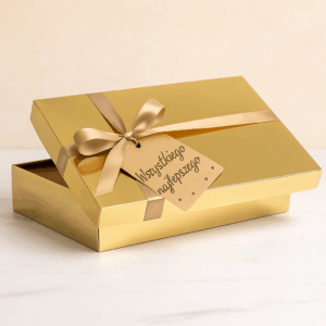 Eleganckie złote pudełko prezentowe przewiązane satynową wstążką z bilecikiem „Wszystkiego najlepszego”